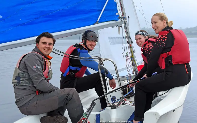 A group of adults in a dinghy with an instructor learning to sail at Draycote Water