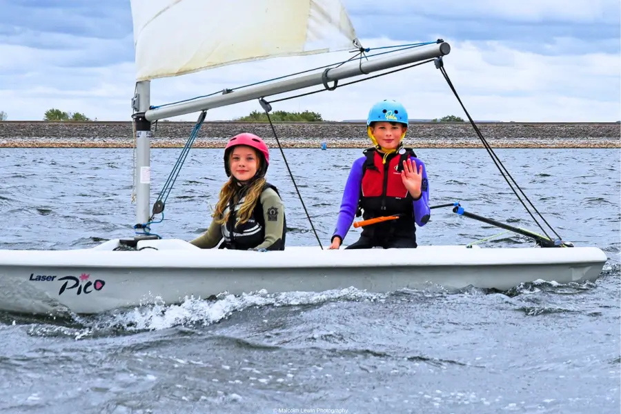 2 children wave while sailing together